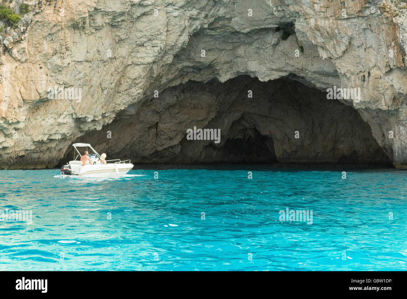 Couple in small boat exploring the blue caves - limestone caves on the west coast of Paxos, Greece, Europe Stock Photo