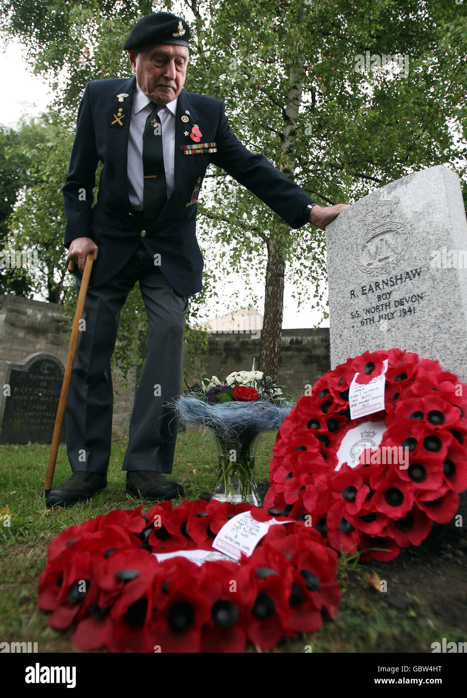 Former machine gunner Alf Tubb stands by a headstone at Comely Bank Cemetery in Edinburgh, in memory of Reginald Earnshaw, his friend and former shipmate who was one of the youngest British service casualties of the Second World War. Stock Photo