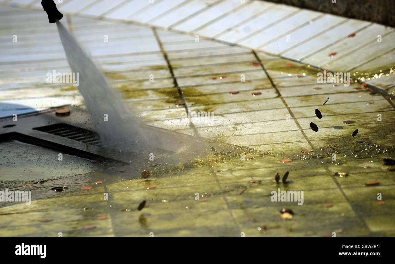 Coins are washed away as workers clean algae from the fountains in