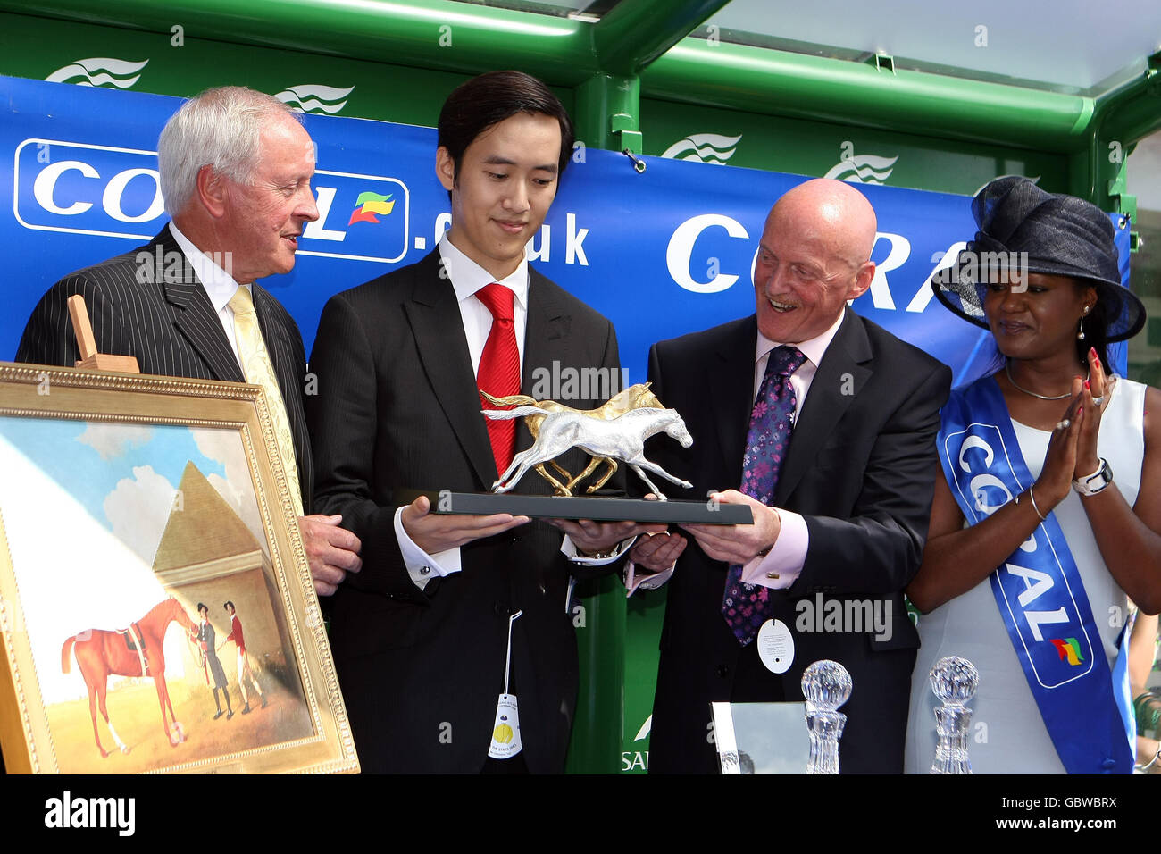 Horse Racing - Coral-Eclipse Day - Sandown Park. Christopher Tsui, owner of Sea The Stars (centre) collects his trophy for winning the Coral Eclipse Stock Photo