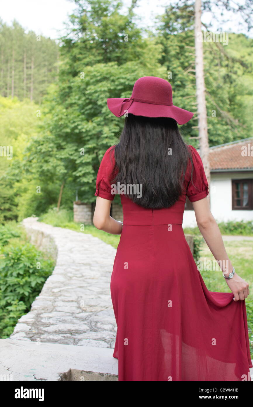 Woman walking the path in park wearing red dress Stock Photo