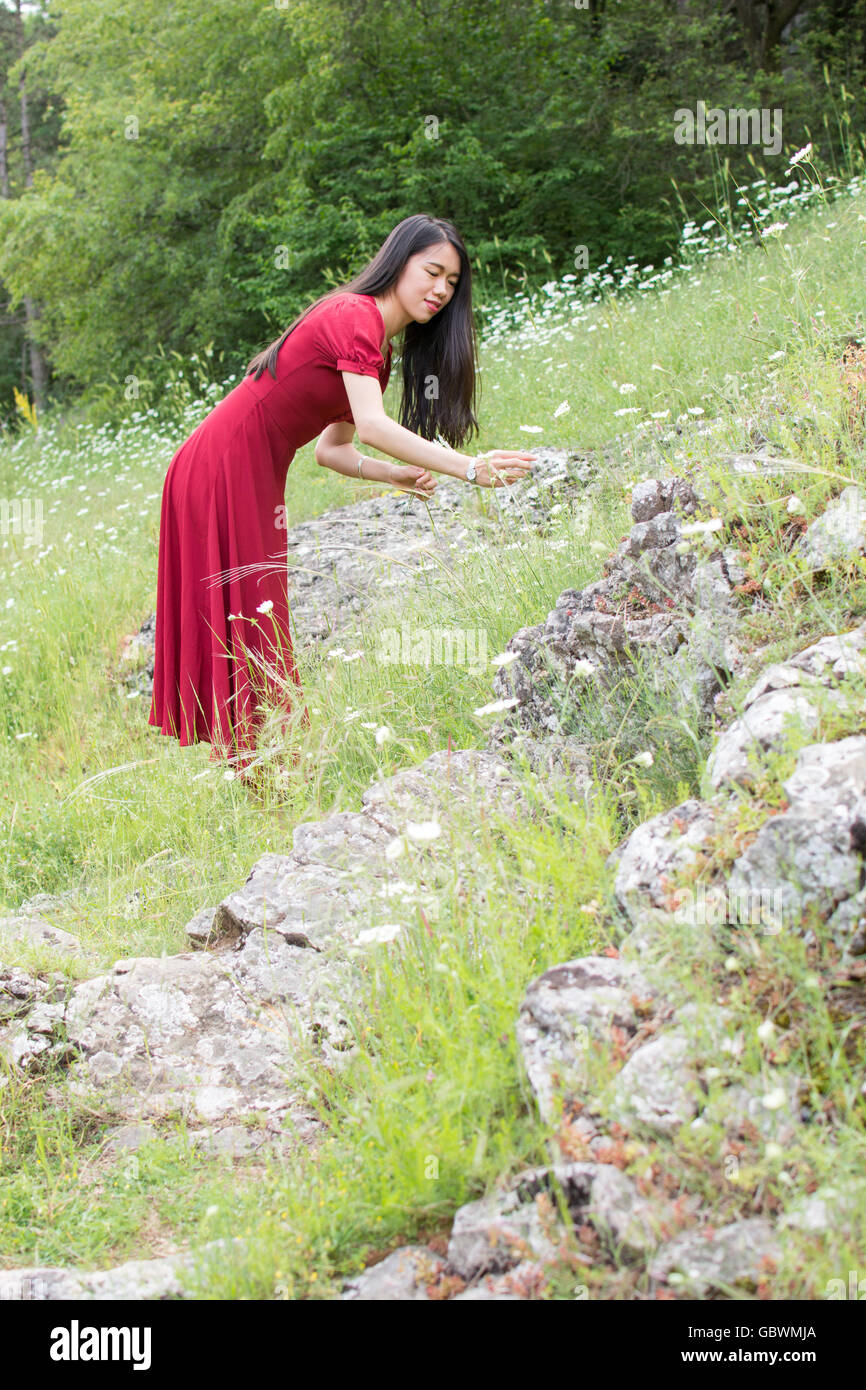 Ypung woman in flower picking wearing red dress Stock Photo