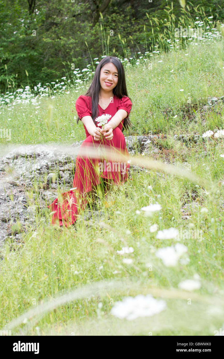 Young woman in flower field wearing red dress Stock Photo - Alamy