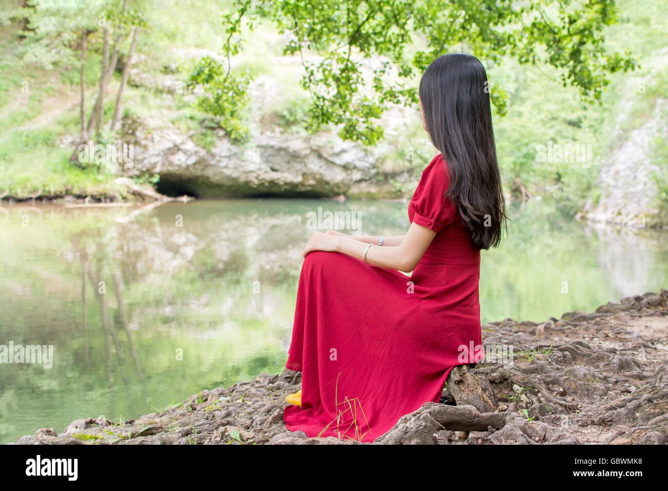 Fashionable woman sitting by the river alone Stock Photo