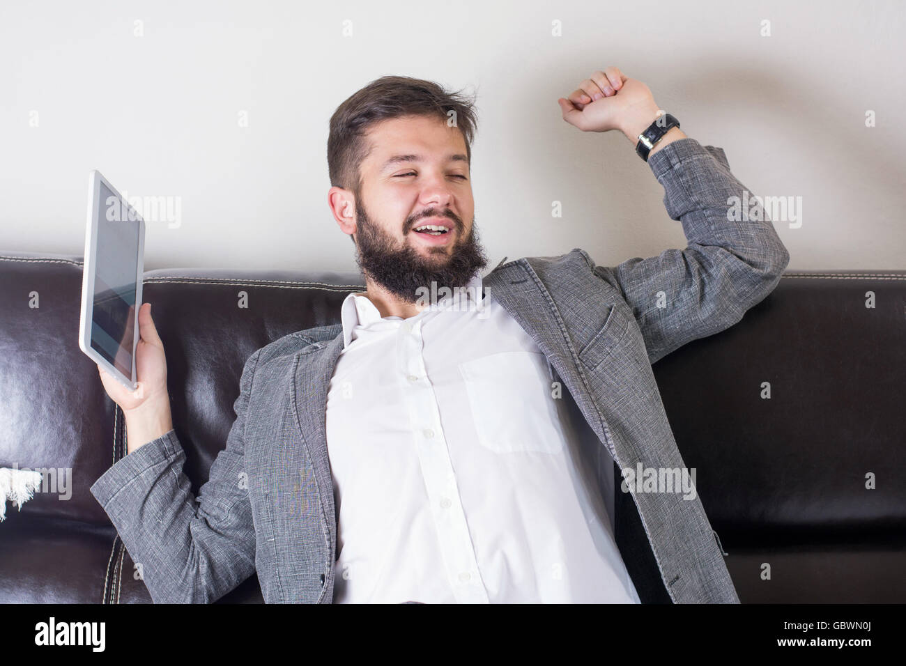Sleepy businessman stretching with a tablet device Stock Photo