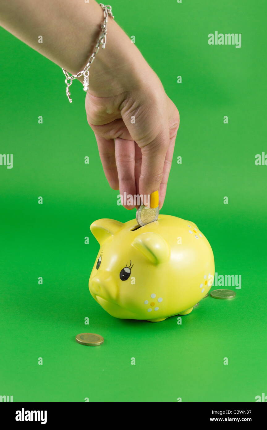 Woman hand inserting a coin into piggy bank Stock Photo - Alamy