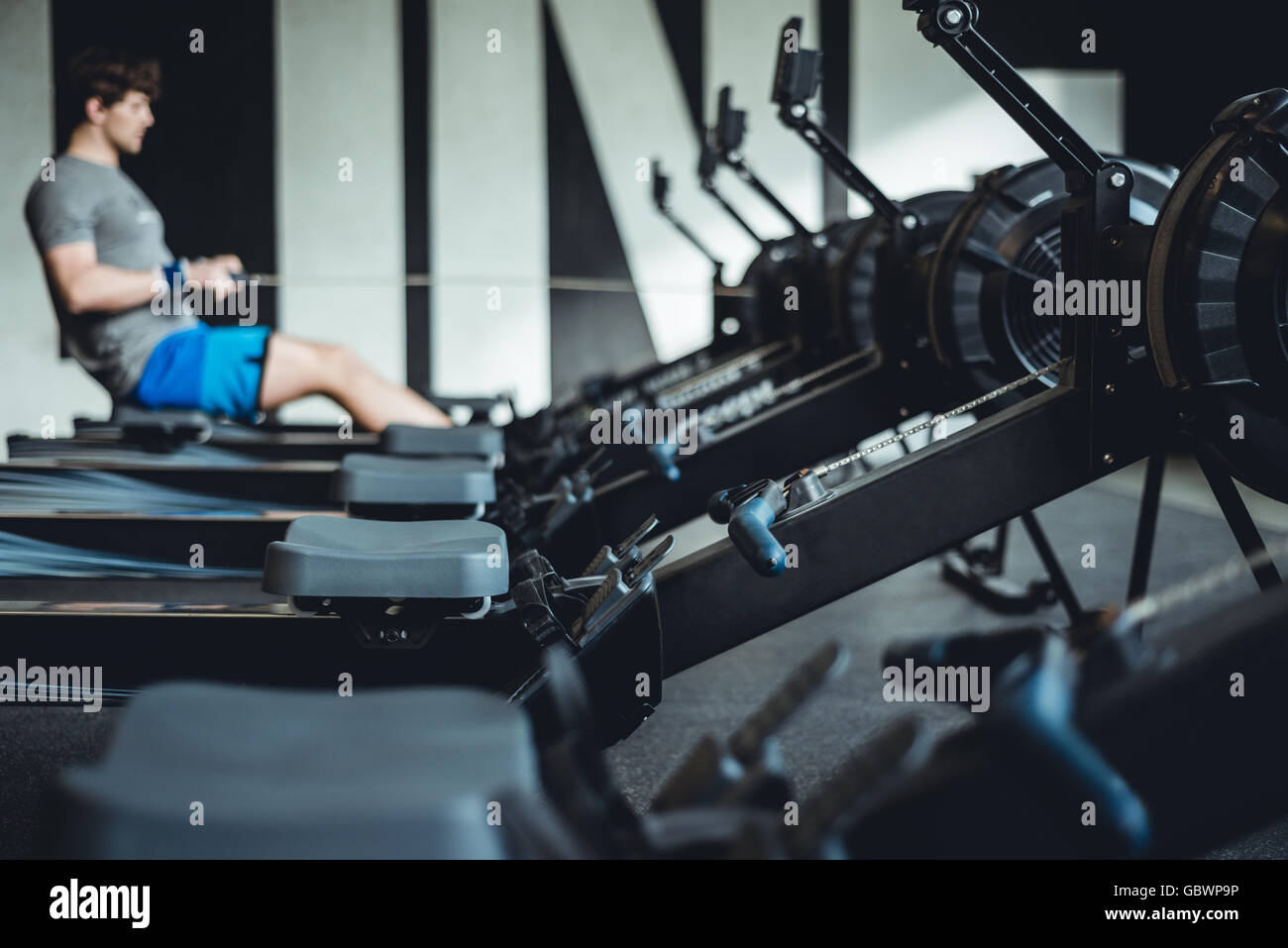 Man working out in gym on rowing machine. Stock Photo