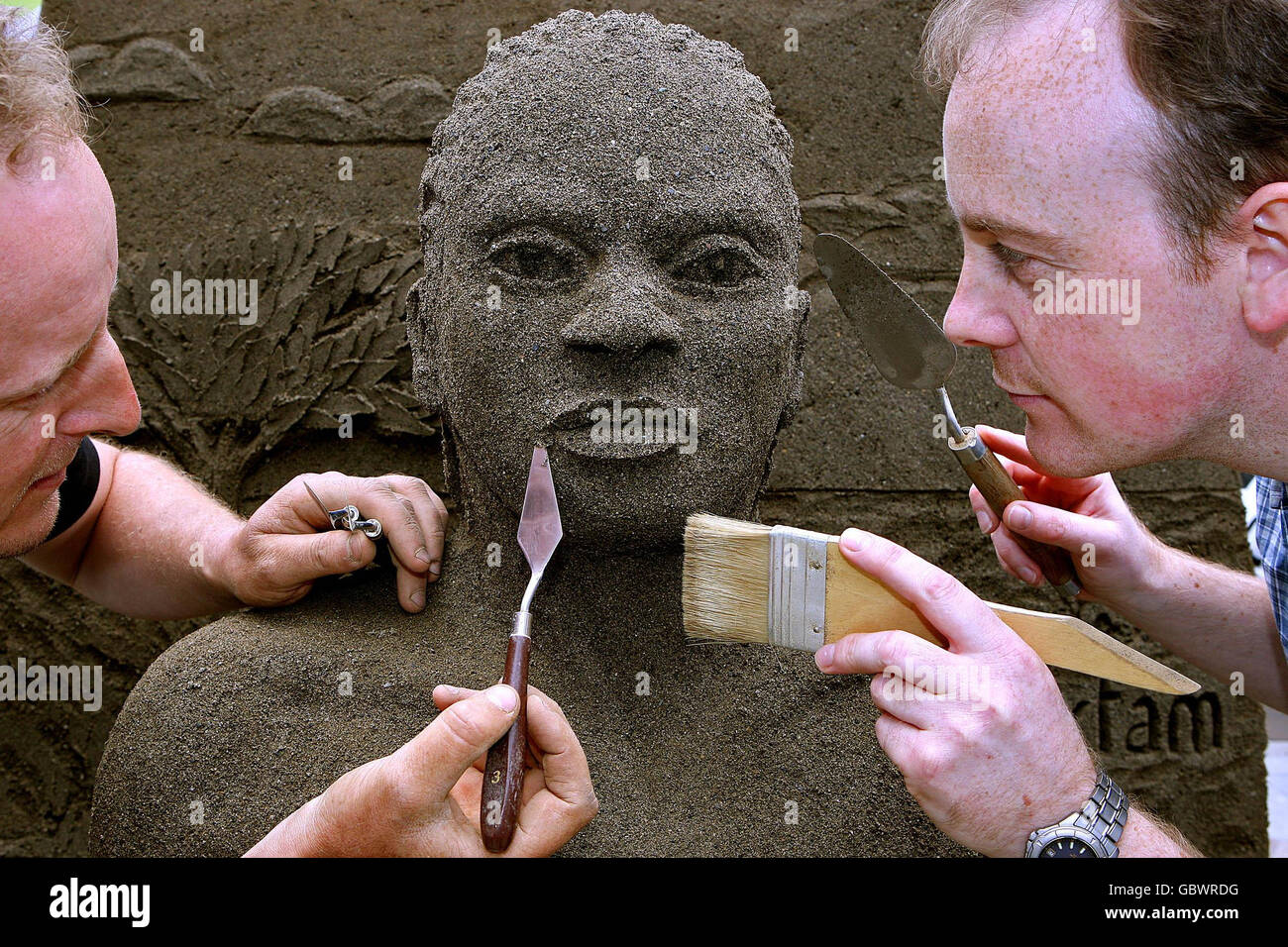 Artist Daniel Doyle (left) and his nephew Nathaniel put the finishes touches his life sized sand sculpture using two tones of sand. The sculpture depicts the human impact of climate change during the Oxfam Ireland launch of Climate Change Destroy's Lives - Lets Face it campaign in Dublin. Stock Photo