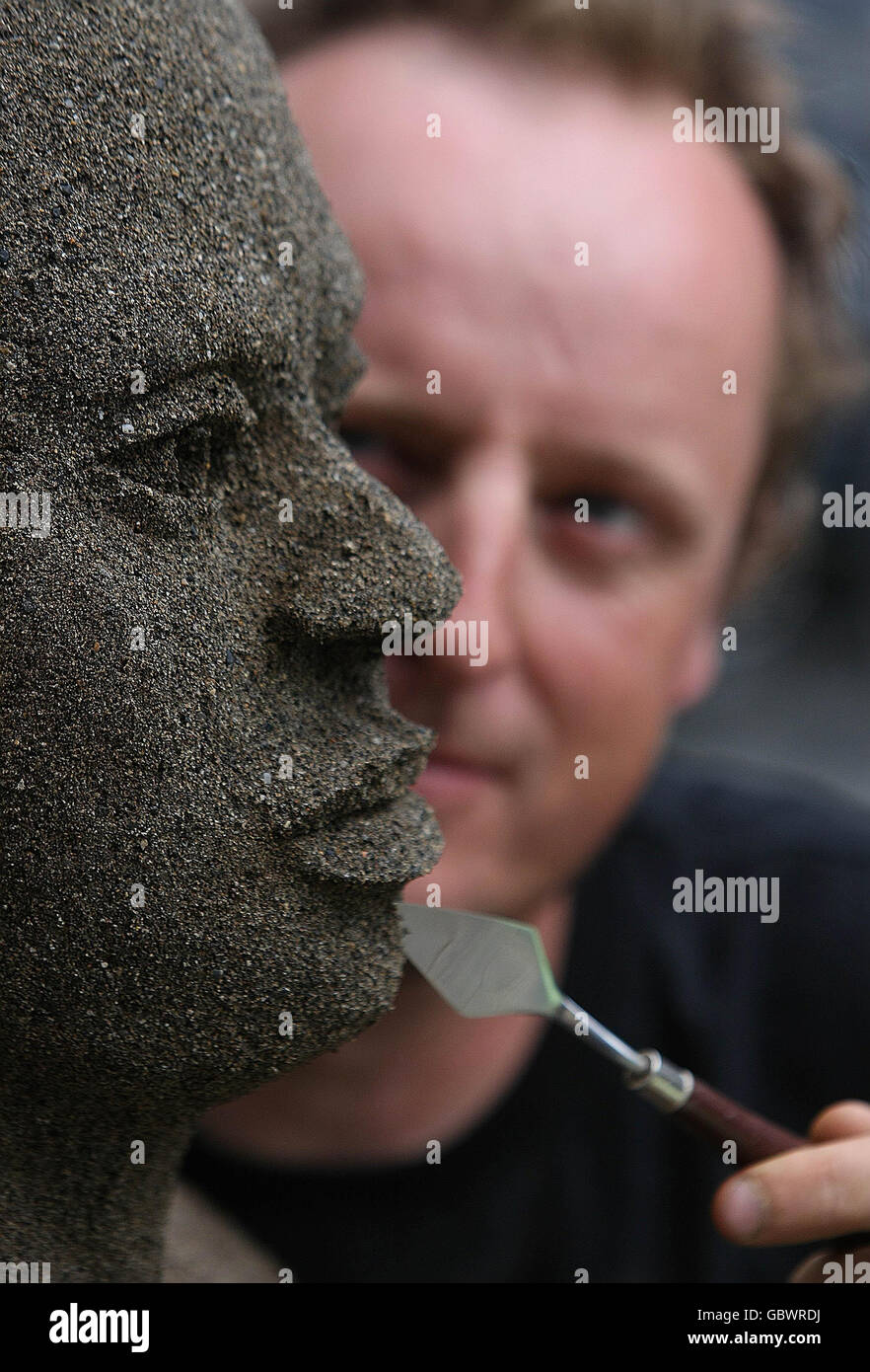 Artist Daniel Doyle puts the finishes touches to his life sized sand sculpture using two tones of sand. The sculpture depicts the human impact of climate change during the Oxfam Ireland launch of Climate Change Destroy's Lives - Lets Face it campaign in Dublin. Stock Photo