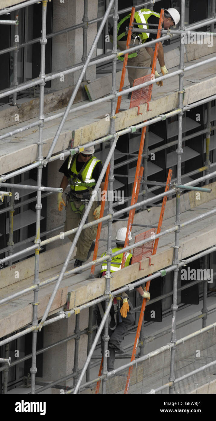 Workers climb ladders on scaffolding on the outside of a newly built