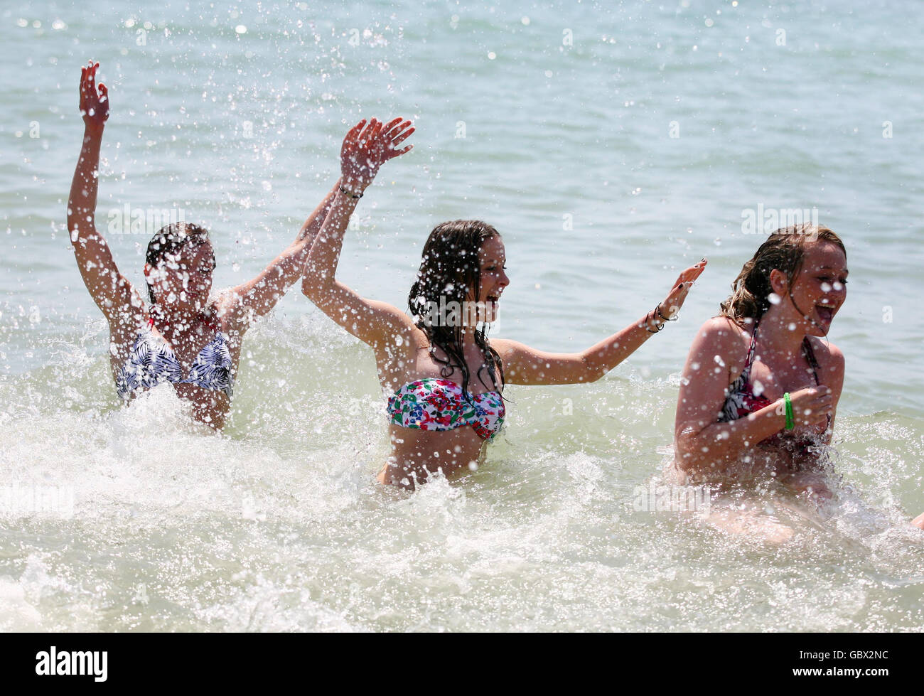 Three friends (names not given) enjoy the surf of Brighton beach in Brighton, East Sussex, as the warm weather continues. Stock Photo