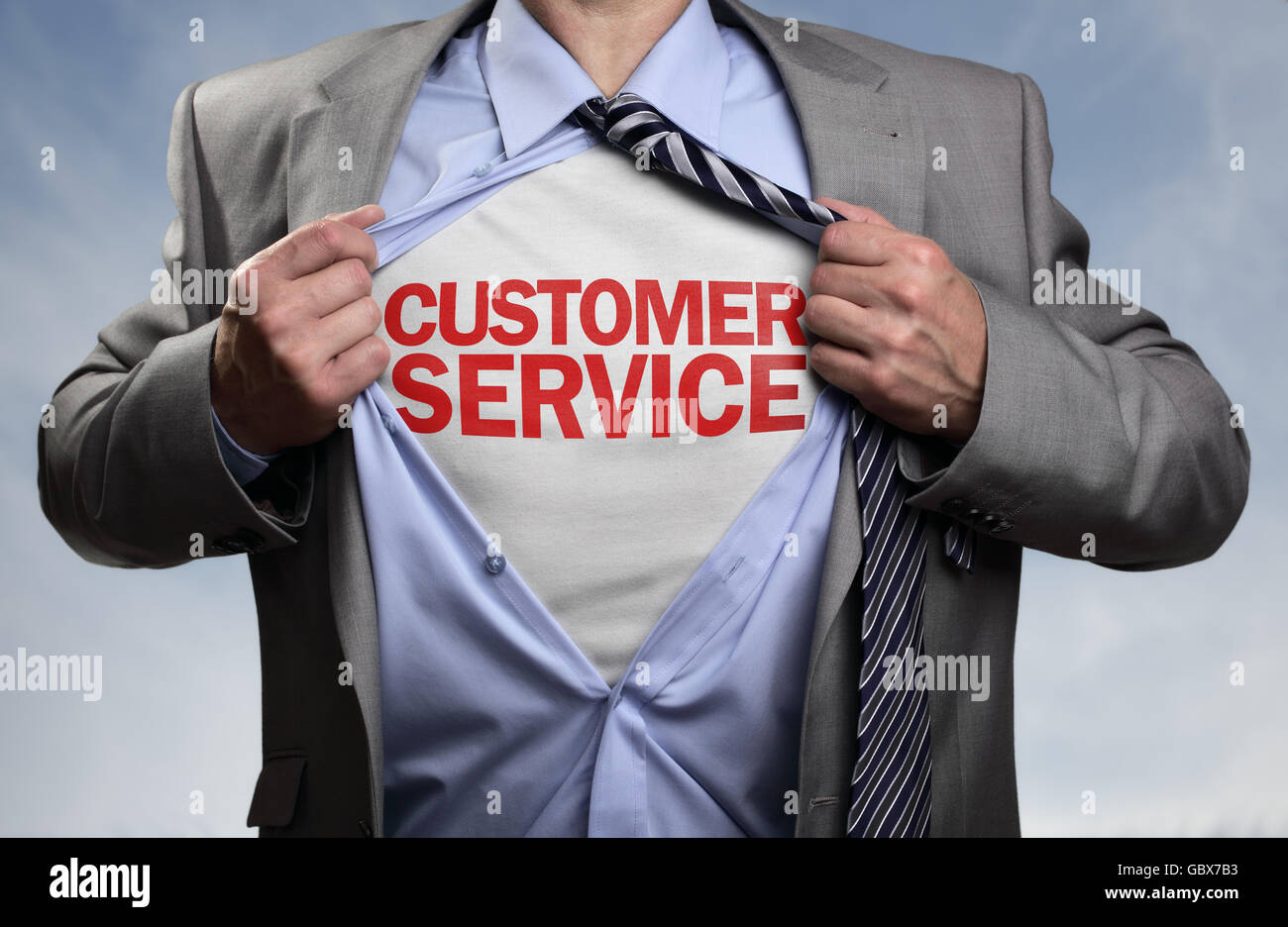 Businessman in classic superman pose tearing his shirt open to reveal t shirt with customer service concept for assistance, cont Stock Photo