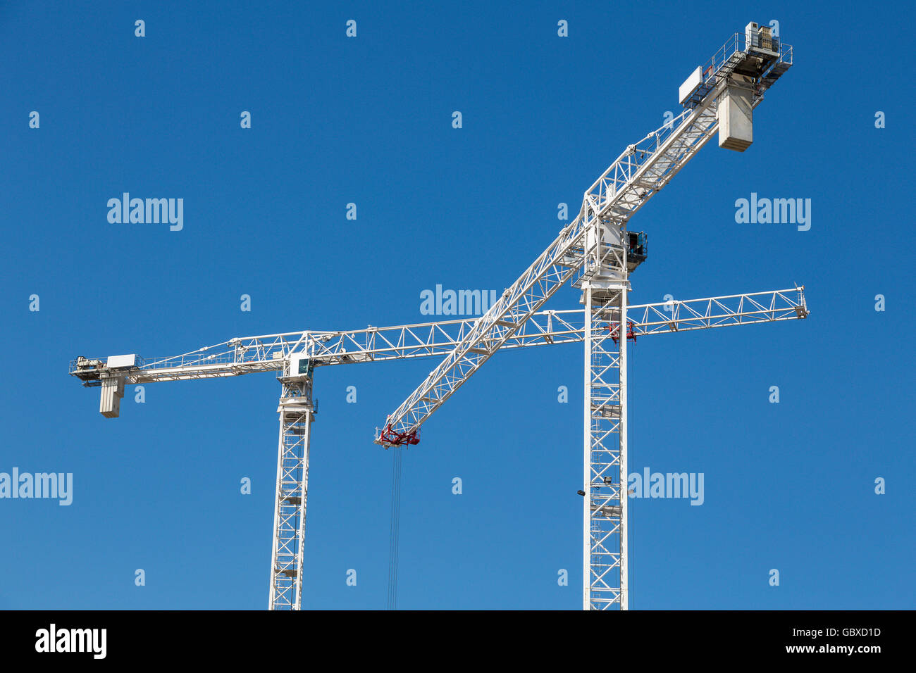 Two tower cranes work in London against blue sky Stock Photo