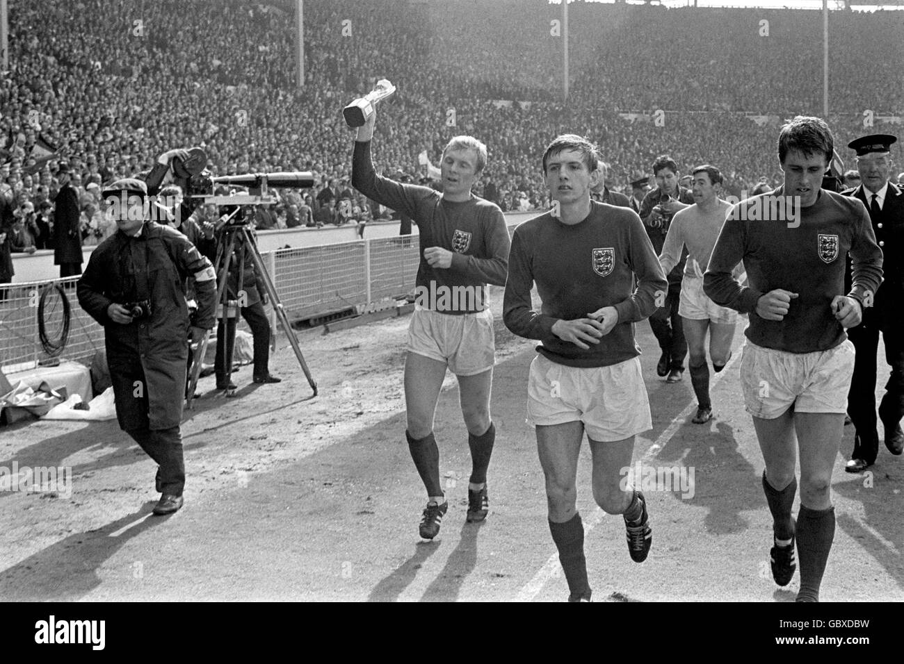 England captain Bobby Moore (l) parades the World Cup around Wembley after his team's 4-2 win, alongside goalscorers Martin Peters (second l) and Geoff Hurst (r), and goalkeeper Gordon Banks (second r) Stock Photo