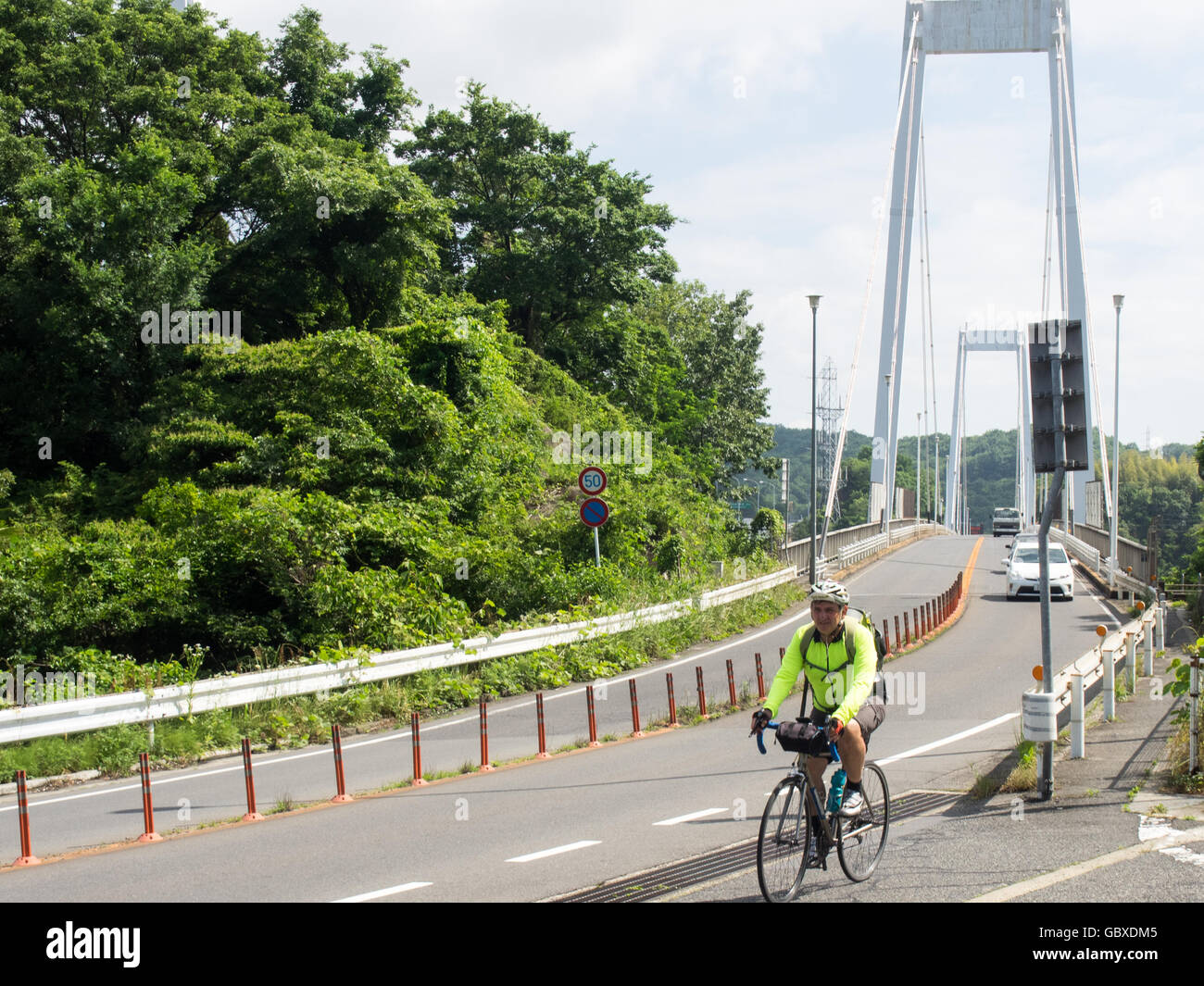 A touring cyclist riding off the Onomichi bridge connecting Onomichi on Honshu and the island Mukaishima. Stock Photo
