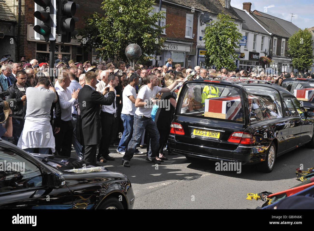 Mourners throw flowers as eight hearses carrying the bodies of eight British soldiers killed during the Army's bloodiest 24 hours in Afghanistan, make their way through the Wiltshire village of Wootton Bassett. Stock Photo