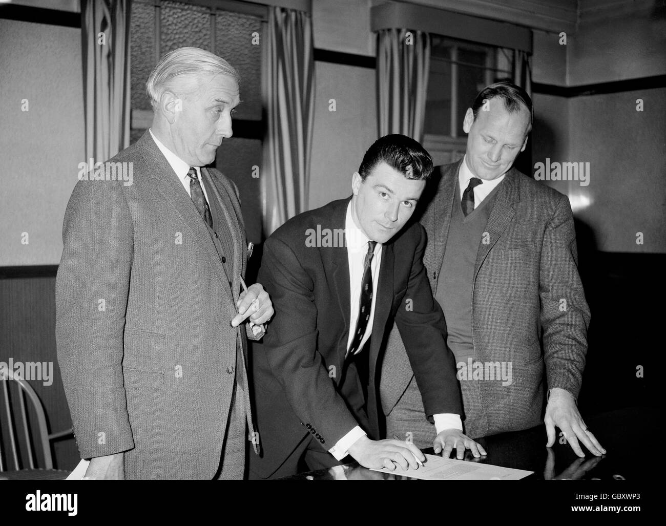 Soccer - Football League Division One - Johnny Byrne Signs For West Ham United. Johnny Byrne (c) signs for West Ham United, watched by manager Ron Greenwood (r) and Crystal Palace manager Arthur Rowe (l) Stock Photo