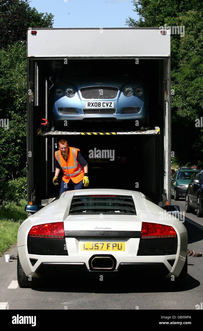 Vehicle transport specialists remove luxury cars from a garage in
