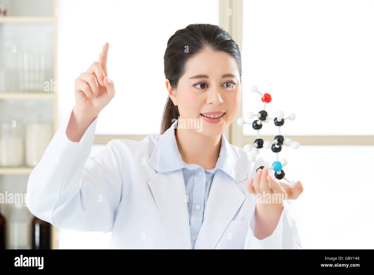 asian female scientist doing research on touch screen and holding molecular model Stock Photo