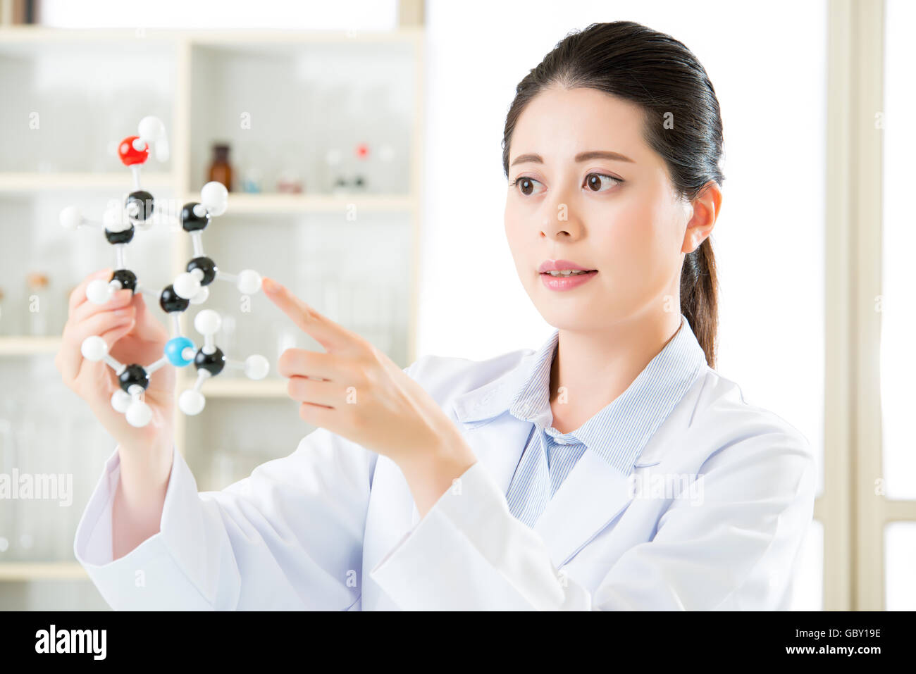asian female scientist holding and looking at molecular model doing the Science research for human longevity Antidote Stock Photo