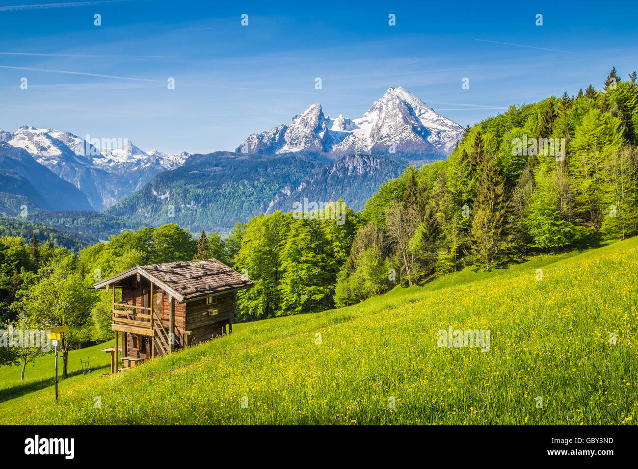 Idyllic mountain scenery with traditional mountain chalet in the Alps on a beautiful sunny day with blue sky in springtime Stock Photo