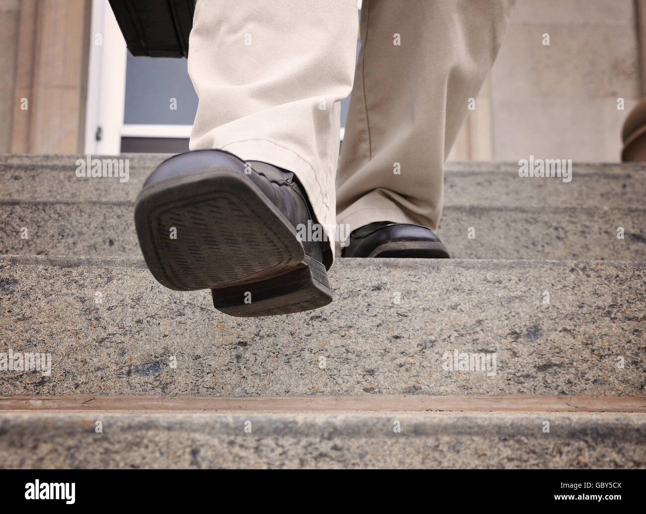 A business man is stepping down the stairs at an office for a power, challenge or motivation concept. Stock Photo