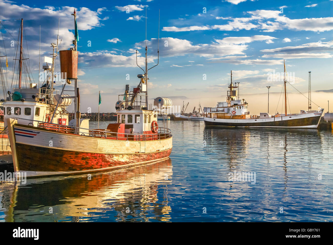 Traditional old wooden fisherman boats lying in the harbor of Husavik in beautiful golden evening light at sunset, Iceland Stock Photo