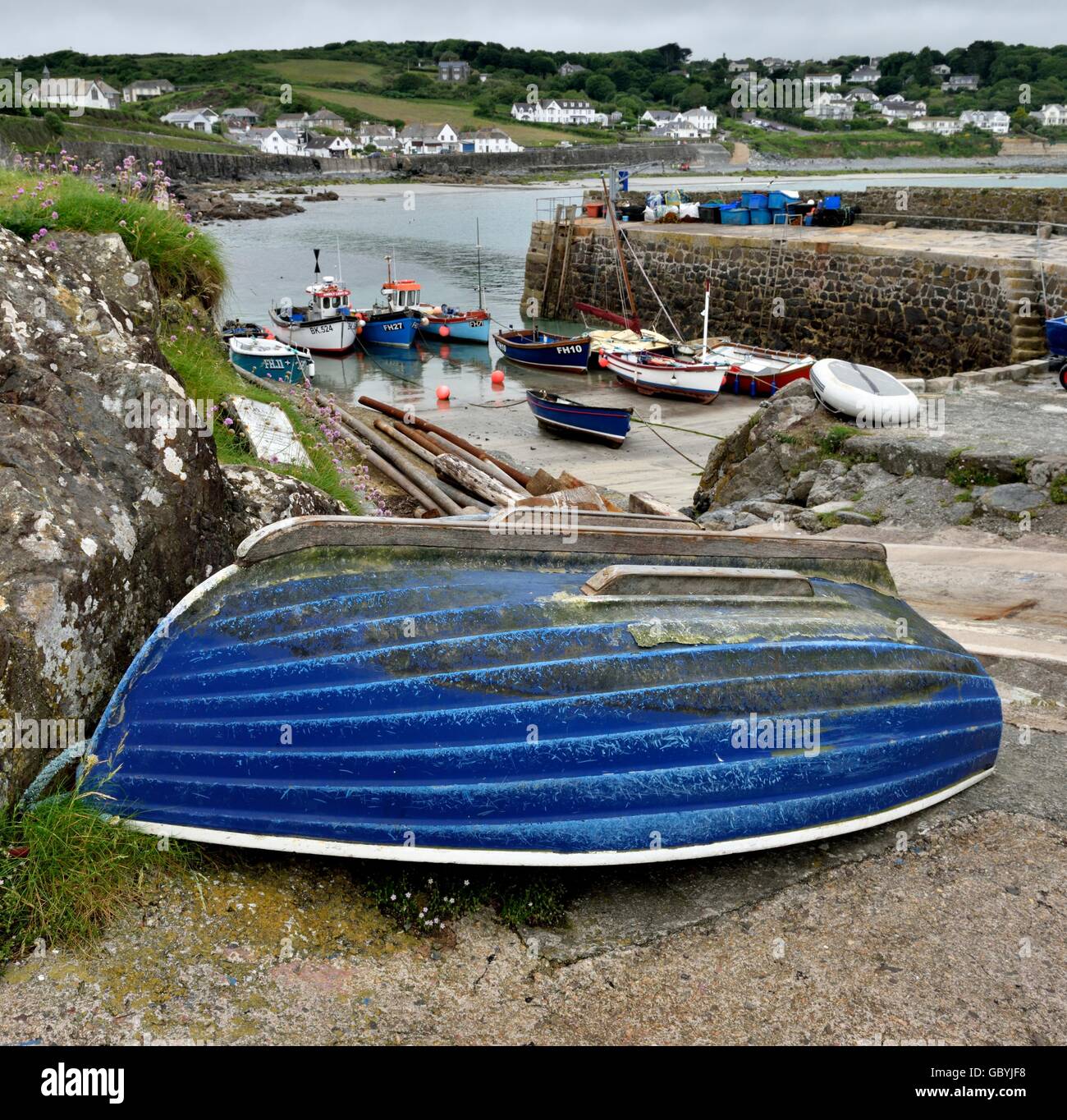A blue rowing boat upside down in Coverack harbour Cornwall England UK