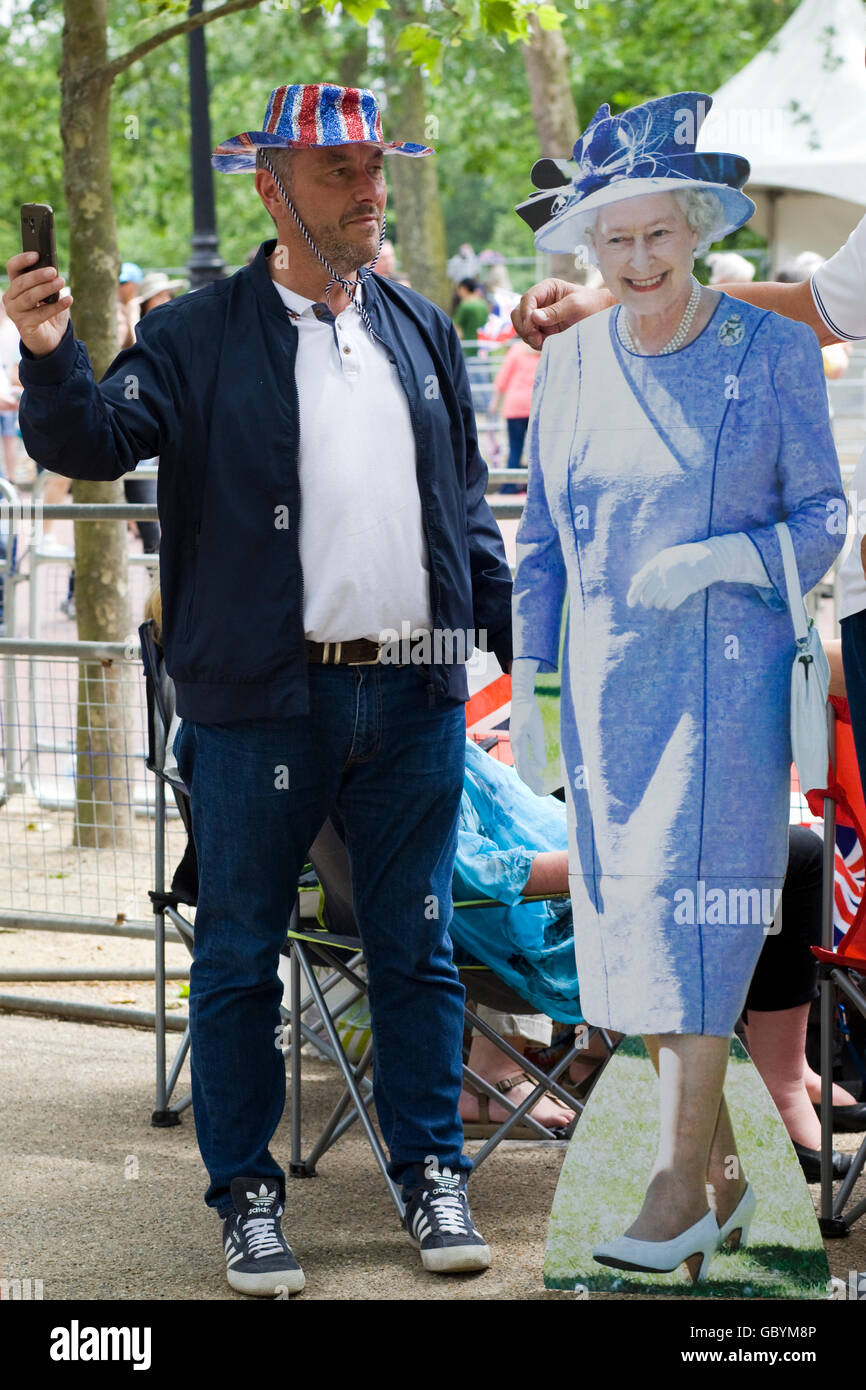 man taking a selfie with a cardboard cutout of the Queen Stock Photo