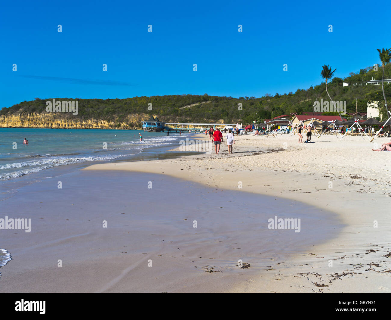 dh Dickenson Bay beach ANTIGUA CARIBBEAN Tourist couple walking sea shore West Indies holiday Stock Photo