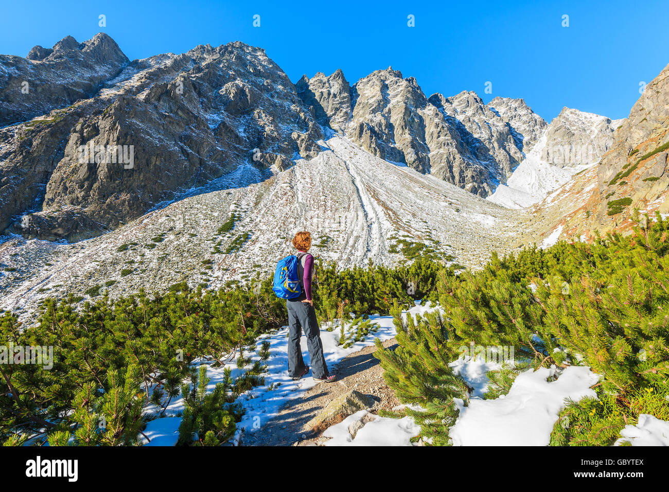 Young woman tourist looking at mountains covered with snow in autumn landscape of Hincova valley, Tatra Mountains, Slovakia Stock Photo