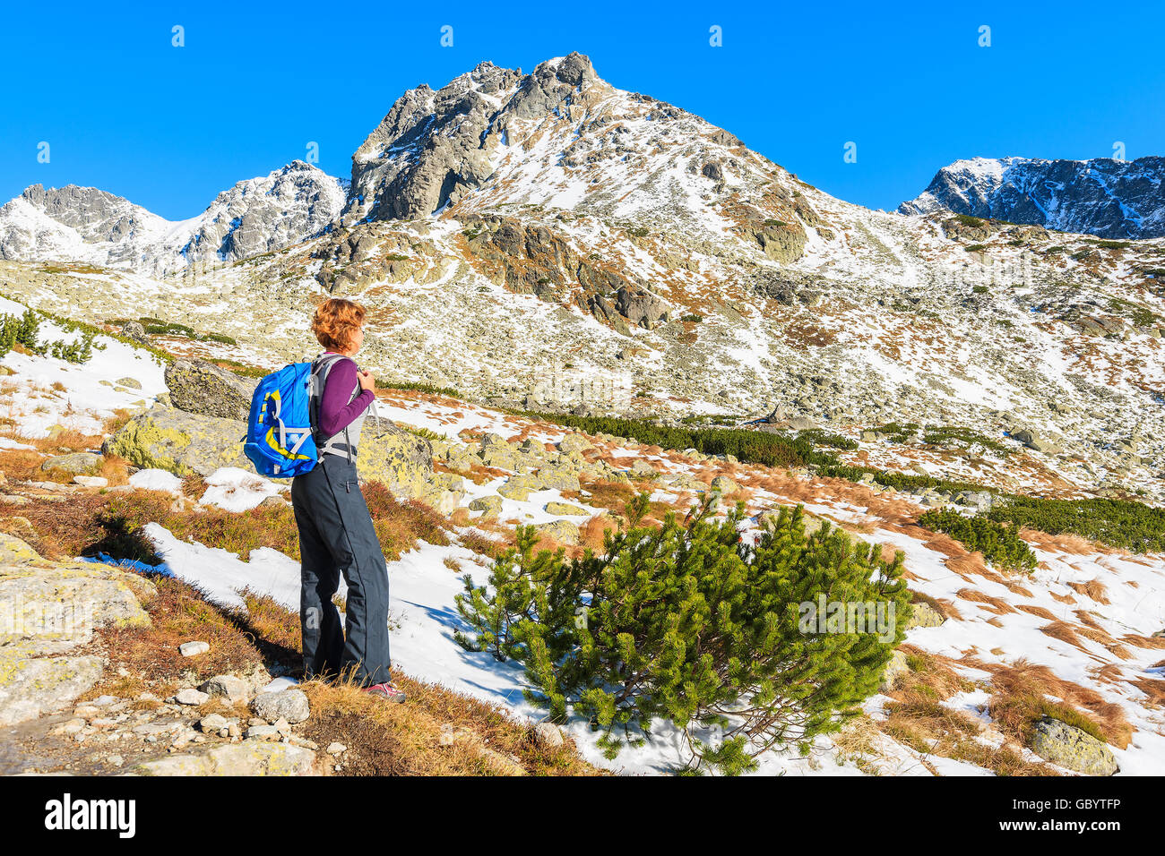 Young woman tourist looking at mountains covered with snow in autumn landscape of Hincova valley, Tatra Mountains, Slovakia Stock Photo
