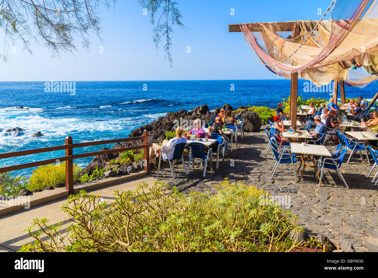 BUENAVISTA DEL NORTE, TENERIFE, NOV 15, 2015: people sitting in a restaurant on coast of Tenerife with Atlantic Ocean in backgro Stock Photo