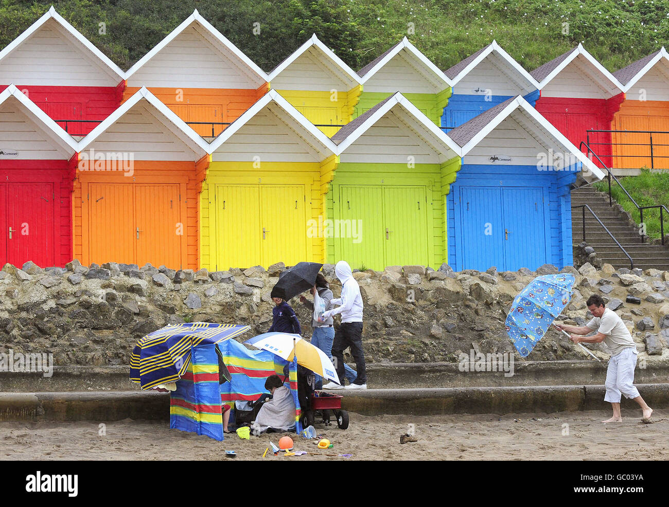 Holiday-makers in heavy rain and strong winds on Scarborough beach. The Met Office had predicted a rainy August, opposed to its earlier statement in April when it issued a seasonal forecast that sparked hopes for a warm and sunny summer with a claim that the UK was 'odds-on for a barbecue summer'. Stock Photo