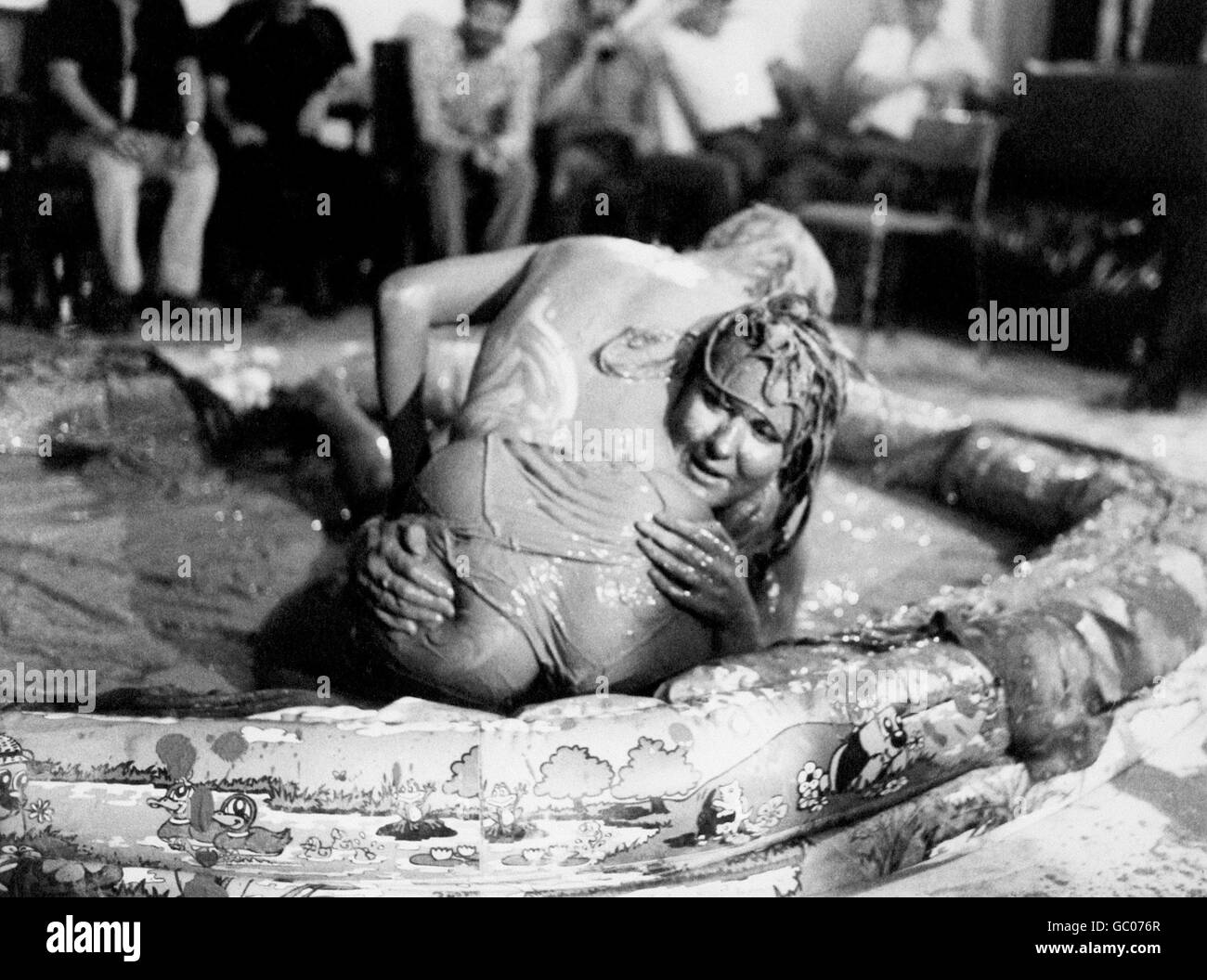 Mud Wrestling. Two female mud wrestlers get to grips with each other in a paddling pool Stock Photo