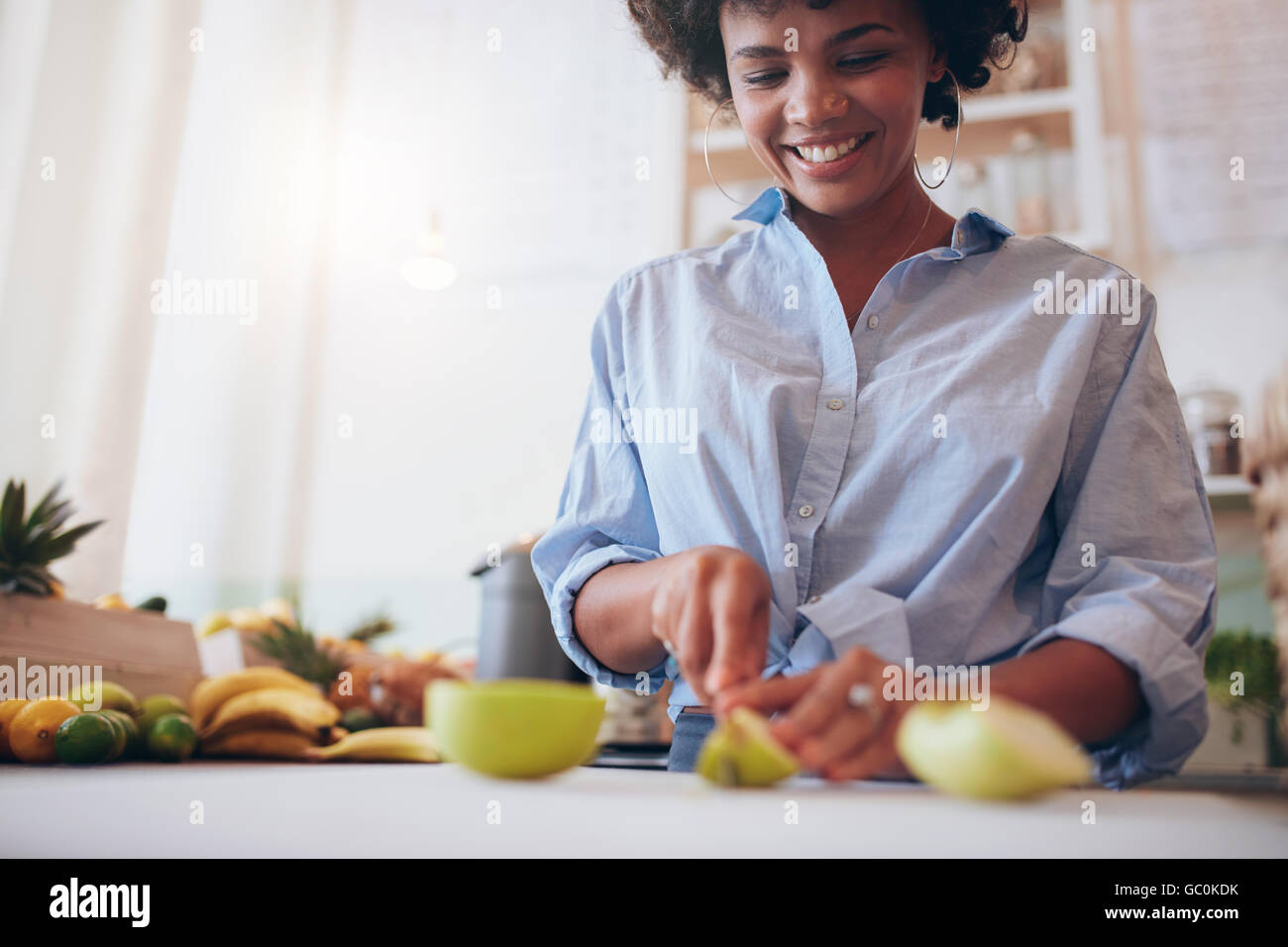 Cropped shot of african woman cutting fruits for making juice at juice bar. Stock Photo