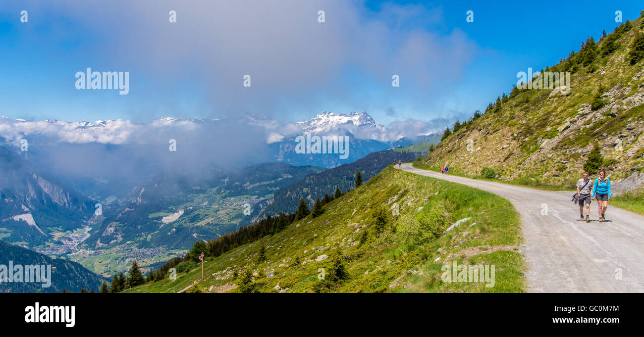 Two people walking up a path in Verbier mountain range Switzerland in summer Stock Photo
