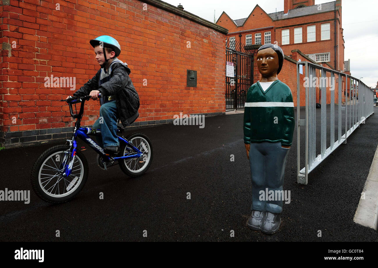 Bradley Ward, 8, from Leicester, cycles past a bollard made to look like a child outside Avenue Primary School in Leicester. Stock Photo
