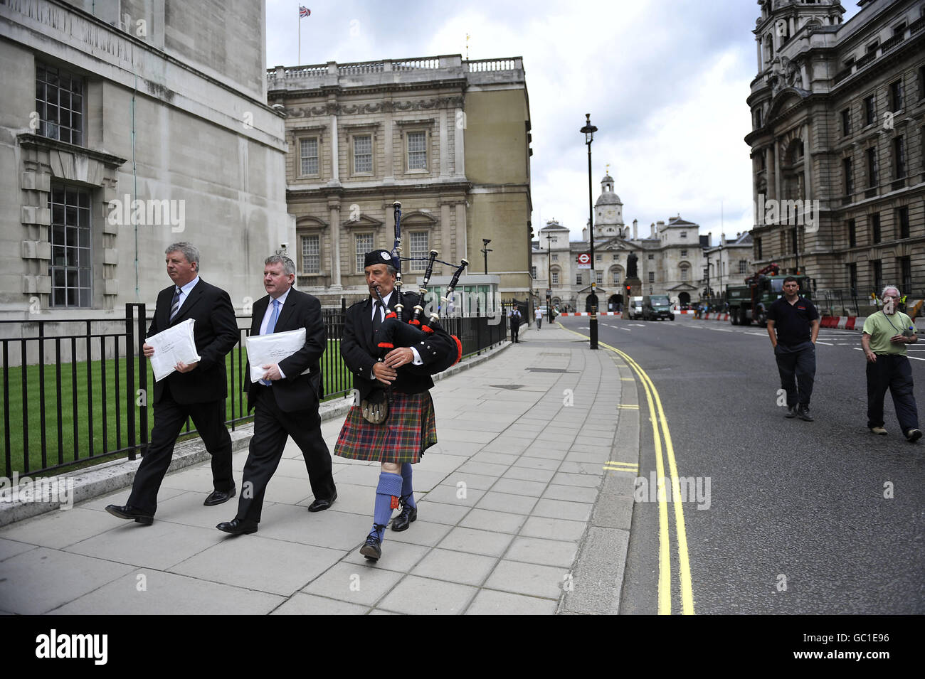 (from left) Angus Campbell, Chairman of the Hebrides Range Taskforce, Angus MacMillan, Chairman of Storas Uibhist and piper James MacKay march along Whitehall to deliver letters to the Ministry of Defence and the Government to fight against plans to scale back a weapons testing range in the Outer Hebrides which will result in job losses. Stock Photo