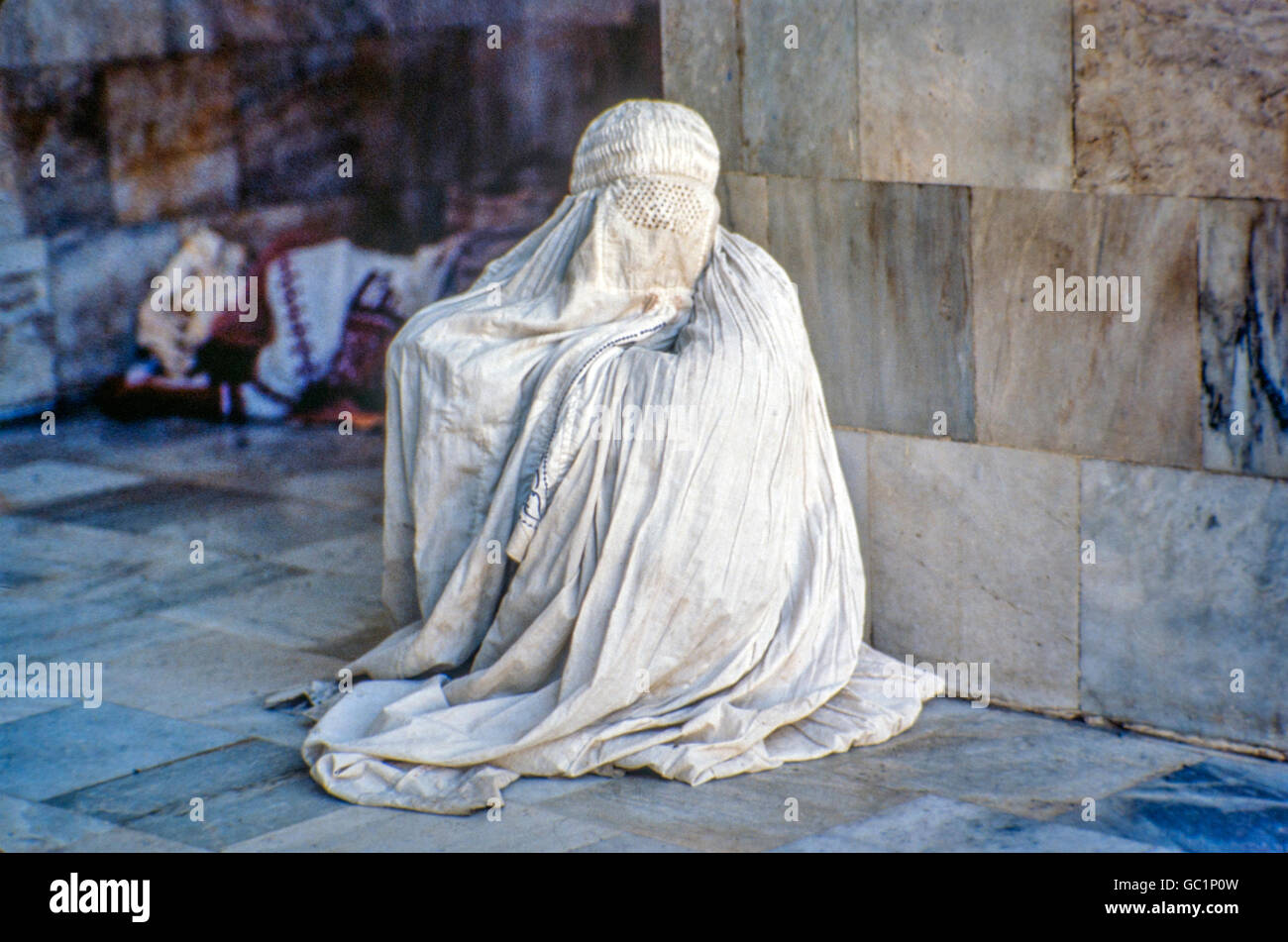 Pakistan woman in Burqa leaning against mosque wall Stock Photo