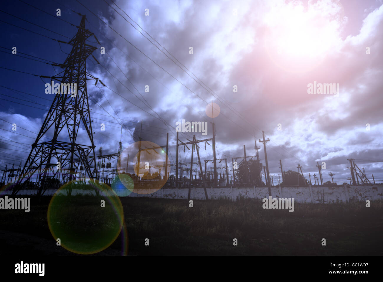 Electricity power station at night with a large pylon and light flare Stock Photo