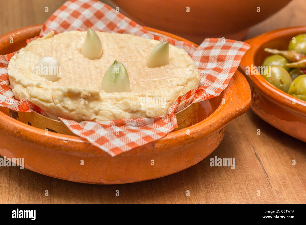 French camembert with cloves of garlic on a wooden table Stock Photo