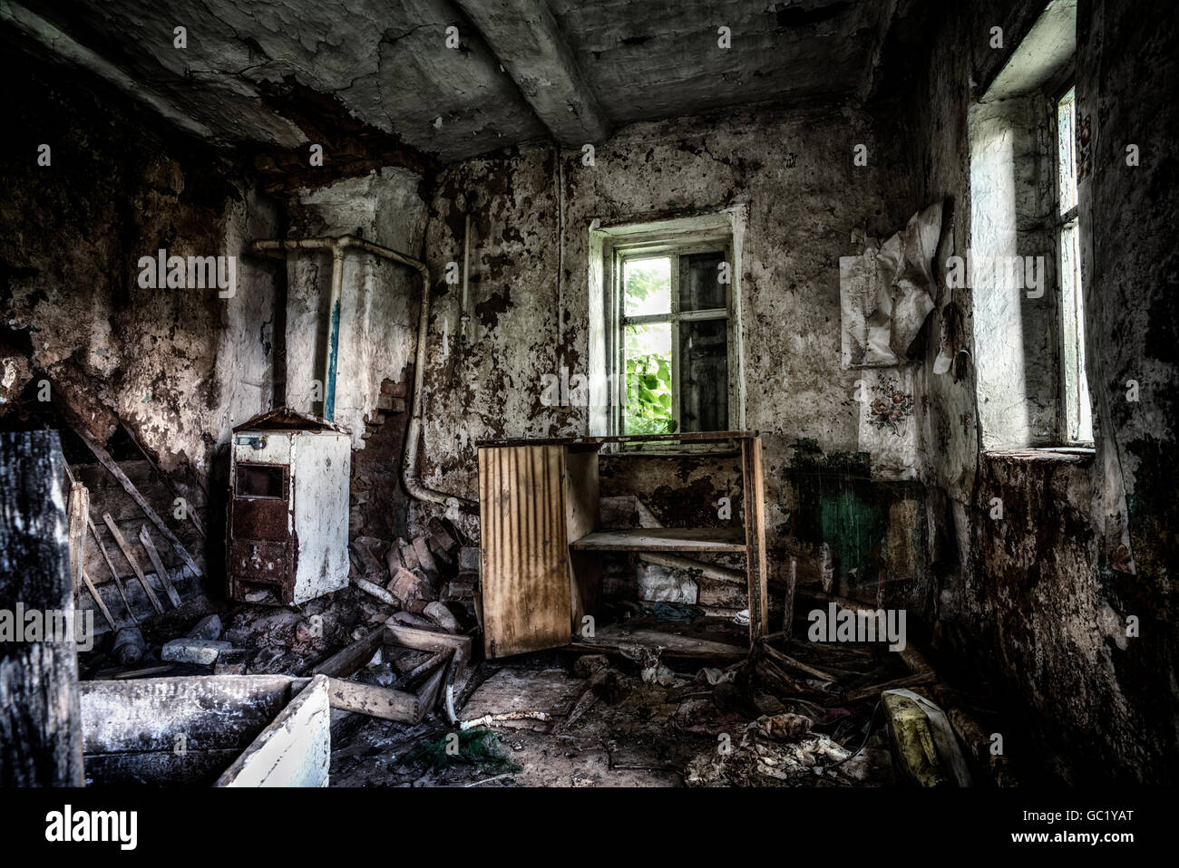 Old forgotten and abandoned home interior in a derelict decaying state with grimy floors and ripped wallpaper. Stock Photo