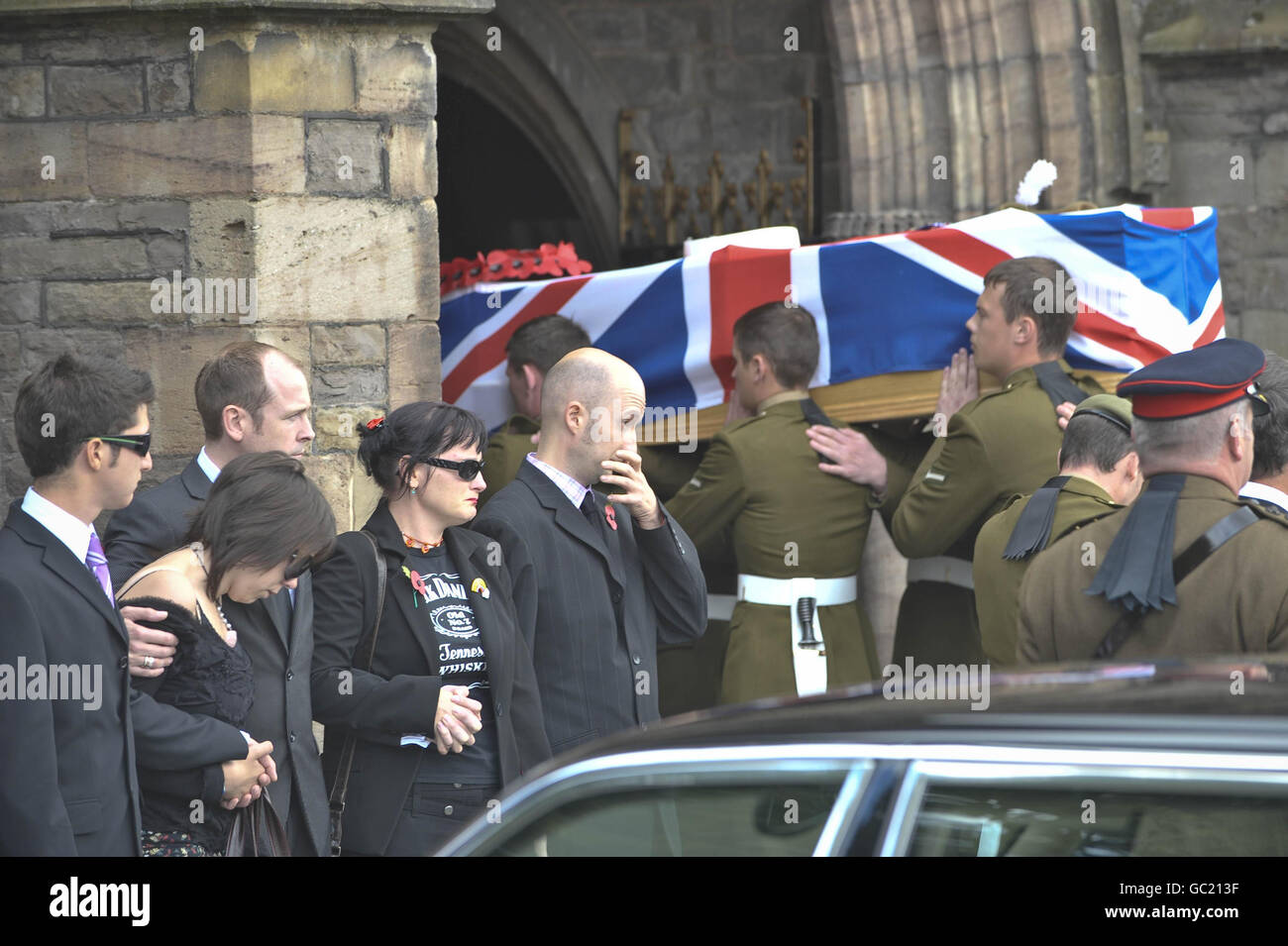 Richard Hunt's family and friends (including Richard's two sisters Fiona, pictured second left, Jayne and Richard's best friend Jonathan Cholakian) watch as Richard's coffin makes its way into Saint Mary's Priory Church, Abergavenny, Wales, where the funeral of Richard is taking place. Stock Photo