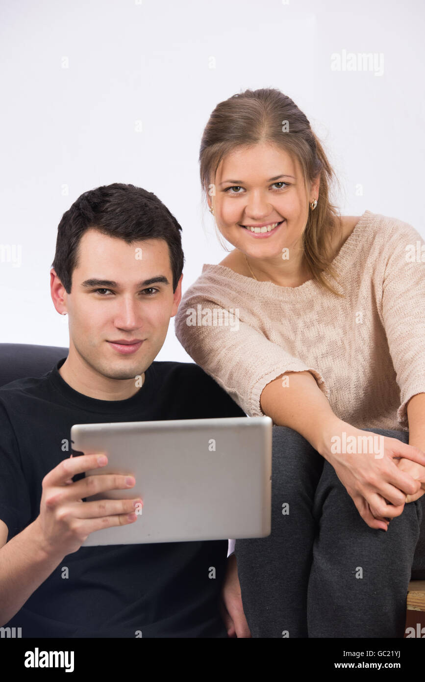 Young casual couple with silver tablet-pc, watching movie or reading news, man in wearing black t-shirt, woman wearing beige blo Stock Photo