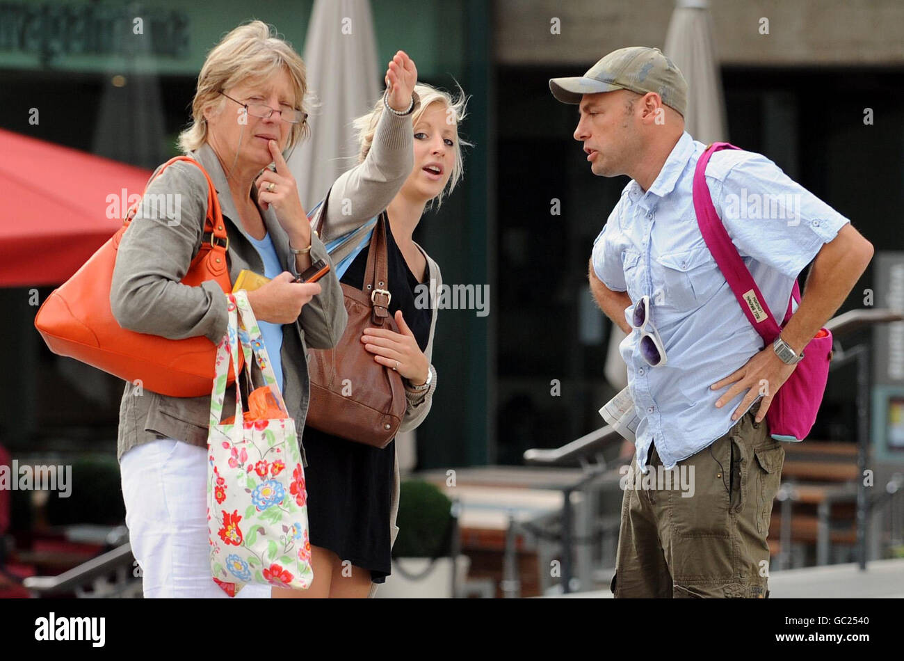 Katie Moore, 23, (centre left) gives directions to an actor posing as a lost tourist who was taking part in The Kindness Offensive on London's Southbank, later awarding Katie with a gold medal for 'random acts of kindness'. Stock Photo