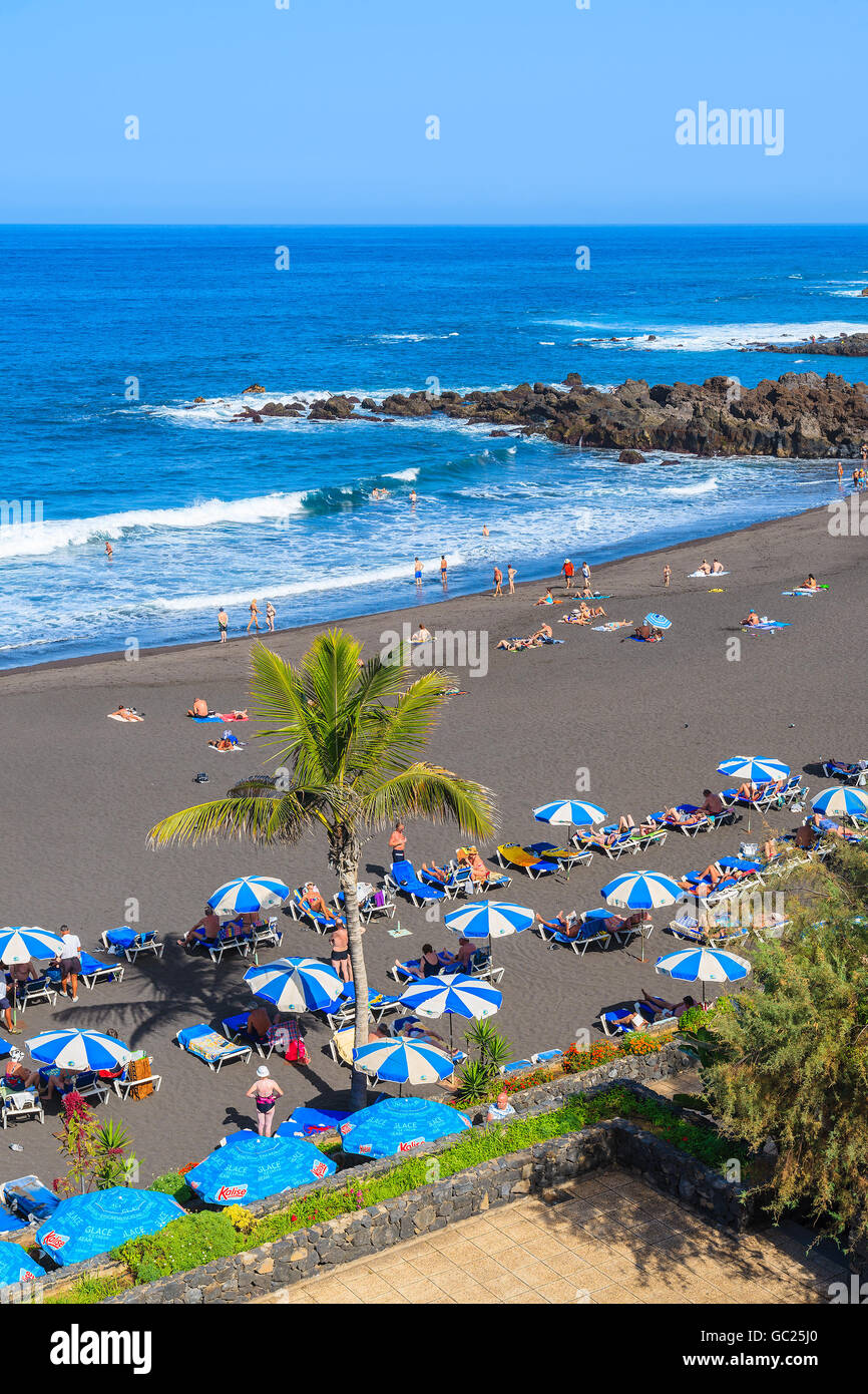 PUERTO DE LA CRUZ BEACH, TENERIFE ISLAND - NOV 16, 2015: A view of beach in Puerto de la Cruz with tourists sunbathing and swimm Stock Photo