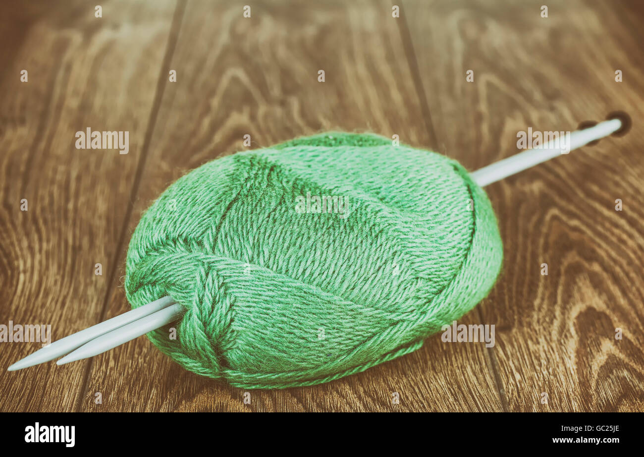 Retro stylized yarn with knitting needles on wooden floor, hobby or retirement concept. Stock Photo