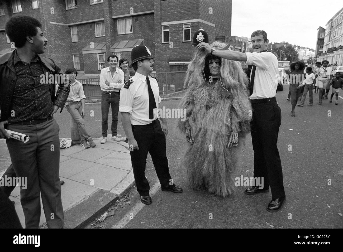 A Notting Hill Carnival witch doctor gets magical aid in the form of a policeman's helmet during peaceful festivities. Stock Photo