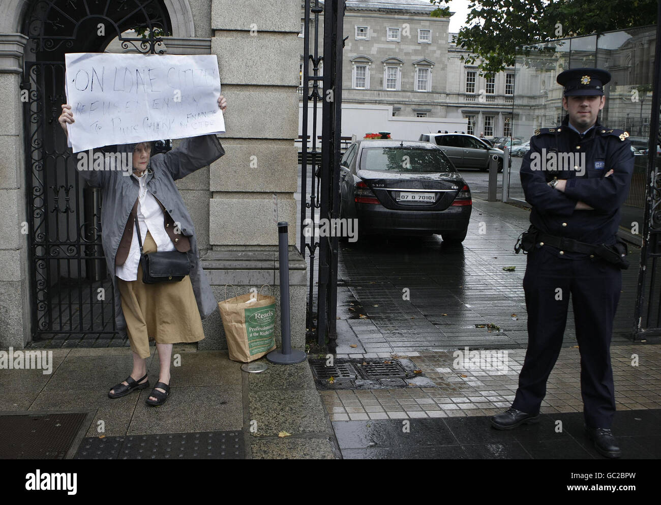 Protester Fionnuala Sherwin is moved on by Guardai after she blocked the intrance to Leinster House in Dublin, for a short time as Finance Minister Brian Lenihan appeared before the Oireachtas Joint Committee on Finance and the Public Service to discuss draft Nama legislation. Stock Photo